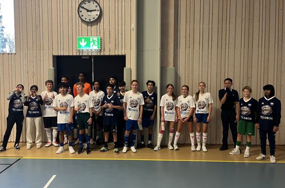 En gruppe mennesker i uniform som står i kø i en gymsal.